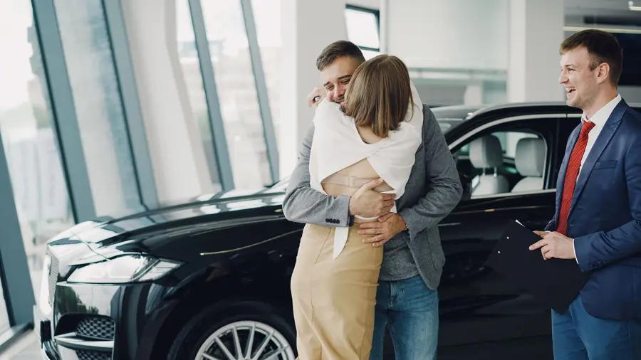 Couple hugging at the dealership, keys in hand